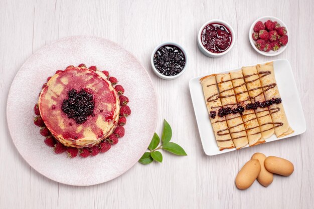 Vista dall'alto deliziose frittelle con fragole e gelatina su torta bianca da scrivania biscotto torta di frutta dolce bacca