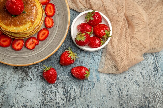 Vista dall'alto deliziose frittelle con fragole fresche alla luce