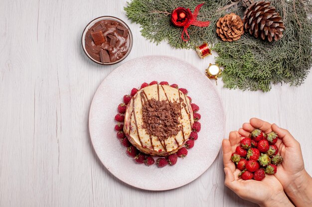 Vista dall'alto deliziose frittelle con fragole su scrivania bianca torta di frutti di bosco torta dolce biscotto