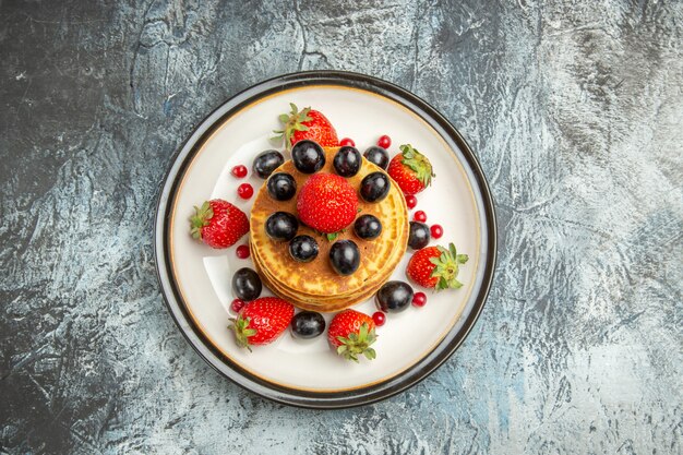 Vista dall'alto deliziose frittelle con frutta e bacche sul dessert di frutta torta superficie scura