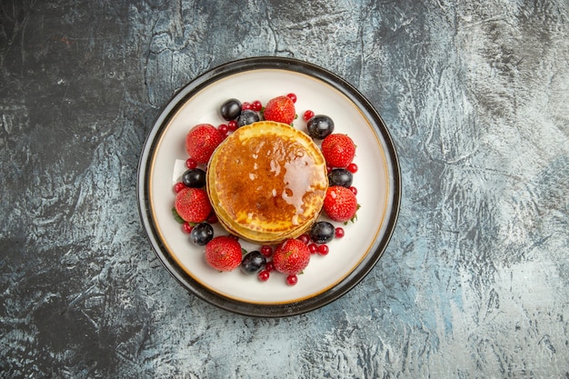 Vista dall'alto deliziose frittelle con frutta e miele alla luce