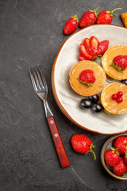 Vista dall'alto deliziose frittelle con frutta sulla torta di frutta torta di superficie scura dolce