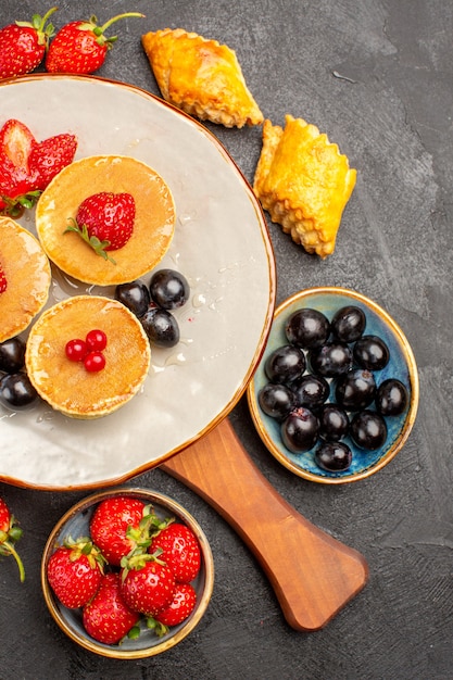 Vista dall'alto deliziose frittelle con frutta sulla torta di frutta torta scura scrivania dolce