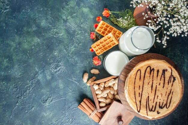 Vista dall'alto deliziose frittelle con latte fresco e noci su superficie blu scuro