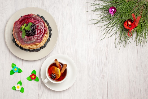 Vista dall'alto deliziose frittelle di gelatina con uvetta gelatina fruttata e tazza di tè su sfondo bianco chiaro marmellata torta gelatina biscotto dessert dolce