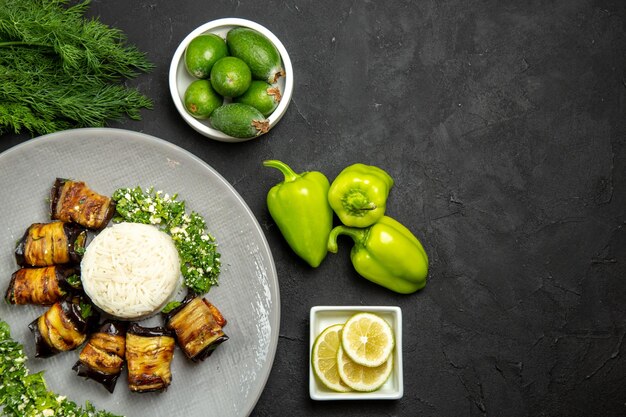 Vista dall'alto deliziose melanzane cotte con riso limone e feijoa su pavimento scuro cena cibo olio da cucina farina di riso