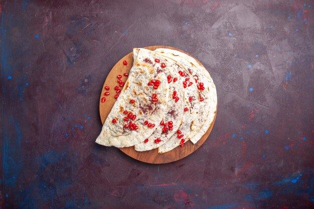 Vista dall'alto deliziose qutab di carne pitas con melograni freschi su pita di pasta di carne superficie viola scuro