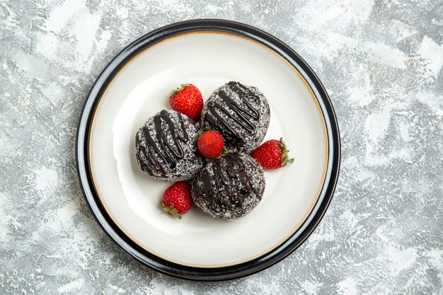 Vista dall'alto deliziose torte al cioccolato con fragole rosse fresche su superficie bianca