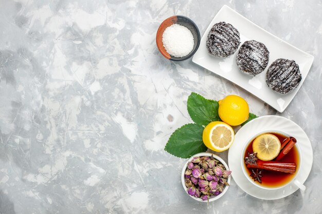 Vista dall'alto deliziose torte al cioccolato con limone e tazza di tè sulla superficie bianca frutta torta biscotto zucchero dolce cuocere biscotto