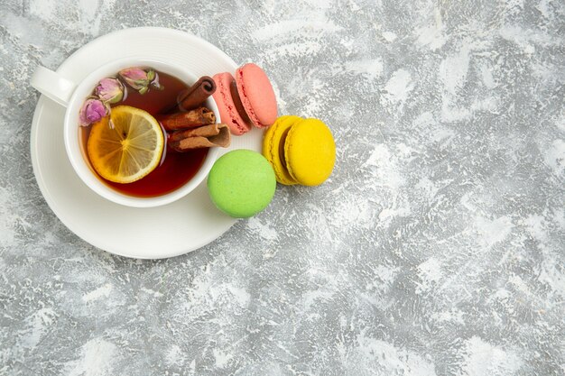 Vista dall'alto deliziose torte colorate di macarons francesi con una tazza di tè su superficie bianca