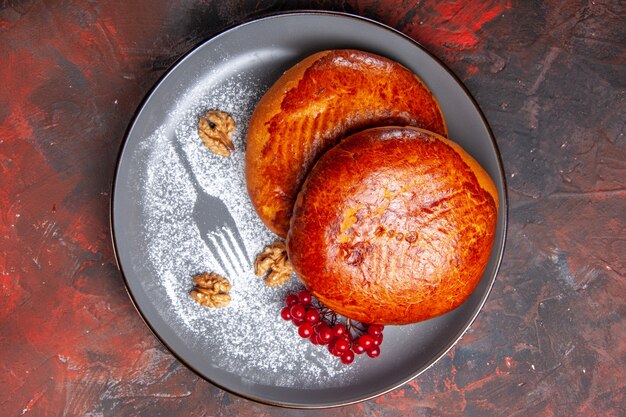 Vista dall'alto deliziose torte con bacche rosse sulla torta di torta di pasticceria dolce tavolo scuro