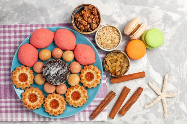 Vista dall'alto deliziose torte con biscotti uvetta e macarons su superficie bianca