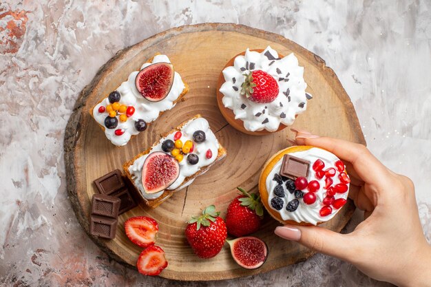 Vista dall'alto deliziose torte con frutta fresca su una scrivania leggera