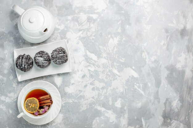 Vista dall'alto deliziose torte con glassa e tazza di tè sullo sfondo bianco chiaro torta di biscotti per il tè cuocere la torta dolce di zucchero