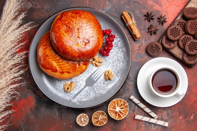 Vista dall'alto deliziose torte con una tazza di tè sulla torta di pasticceria torta dolce tavolo scuro