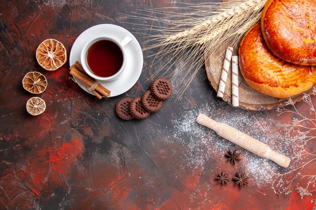 Vista dall'alto deliziose torte con una tazza di tè sulla torta dolce della pasticceria del pavimento scuro