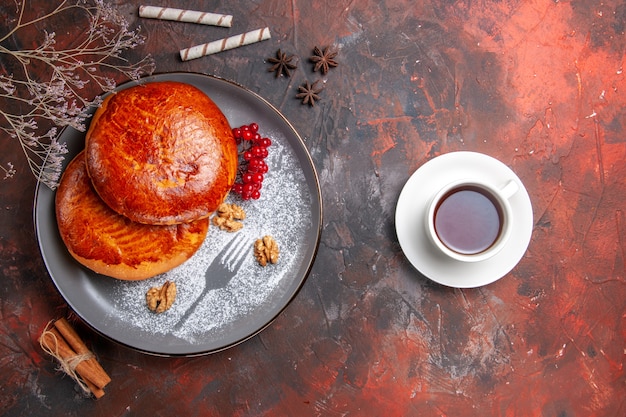 Vista dall'alto deliziose torte con una tazza di tè sulla torta dolce pasticceria torta di tavolo scuro