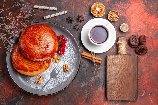 Vista dall'alto deliziose torte con una tazza di tè sulla torta dolce pasticceria torta di tavolo scuro