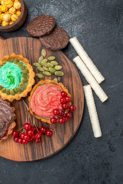 Vista dall'alto deliziose torte cremose con frutta sui biscotti di biscotto dolce tavolo scuro