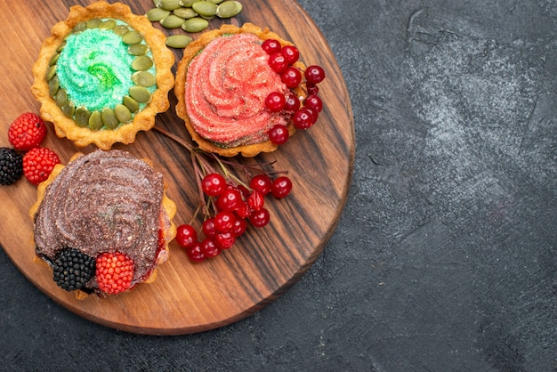 Vista dall'alto deliziose torte cremose con frutti di bosco su dolci biscotti biscotto tavolo scuro