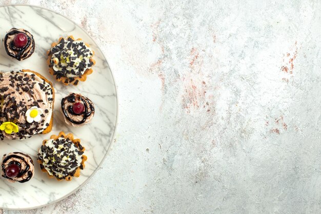 Vista dall'alto deliziose torte cremose con scaglie di cioccolato su una superficie bianca chiara torta biscotto biscotto tè crema dolce