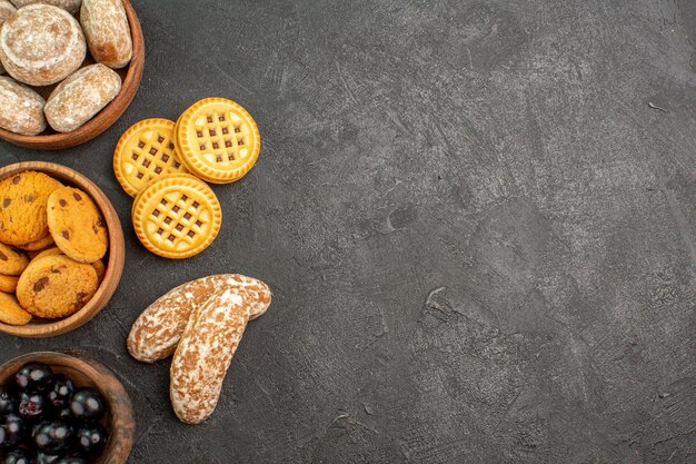 Vista dall'alto deliziose torte dolci con biscotti e olive sulla torta torta di superficie scura dolce