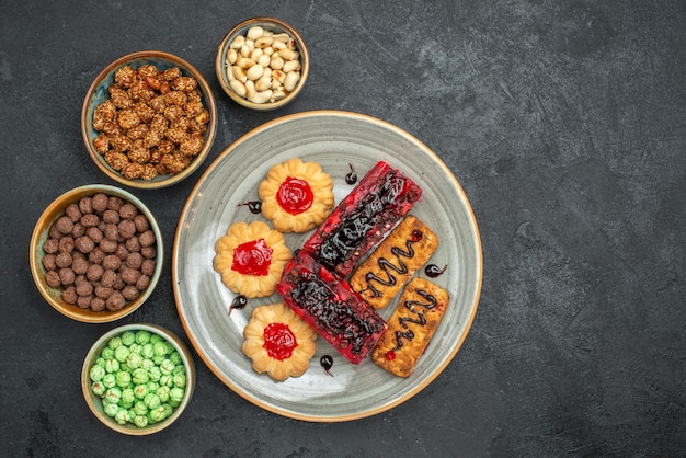 Vista dall'alto deliziose torte fruttate con biscotti e caramelle su sfondo scuro biscotti allo zucchero torta torta biscotto tè dolce