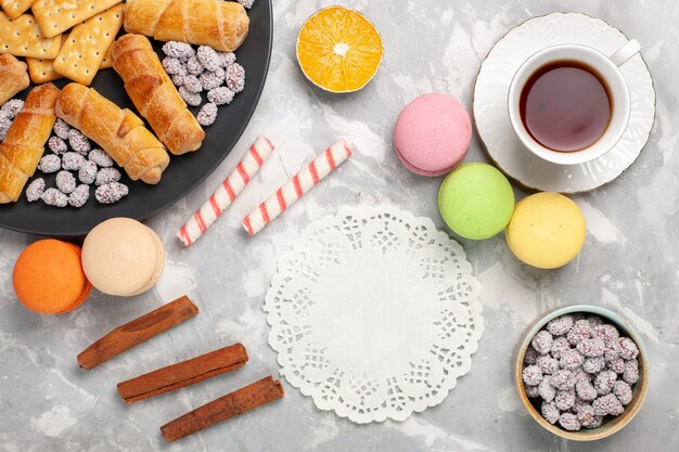 Vista dall'alto deliziosi bagel con cracker macarons e tazza di tè sulla scrivania bianca torta biscotto dolce torta di zucchero biscotto croccante