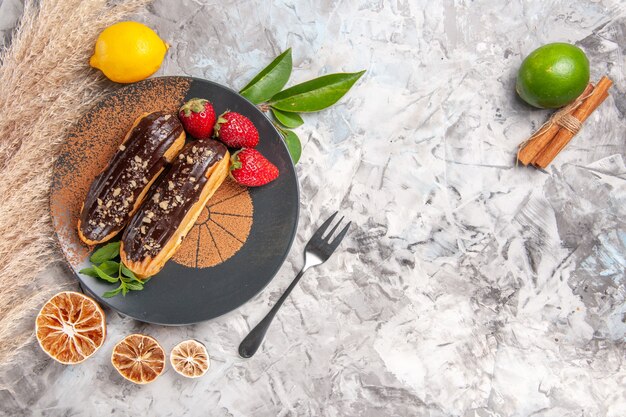 Vista dall'alto deliziosi bignè al cioccolato con fragole su biscotto da dessert con torta bianca