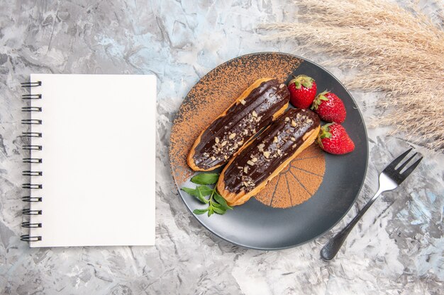 Vista dall'alto deliziosi bignè al cioccolato con fragole su torta di biscotti da dessert da tavola leggera