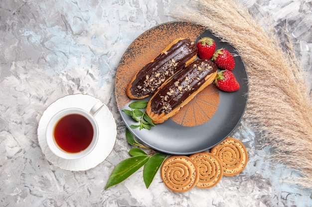 Vista dall'alto deliziosi bignè al cioccolato con una tazza di tè sul dessert al biscotto con torta da tavola bianca