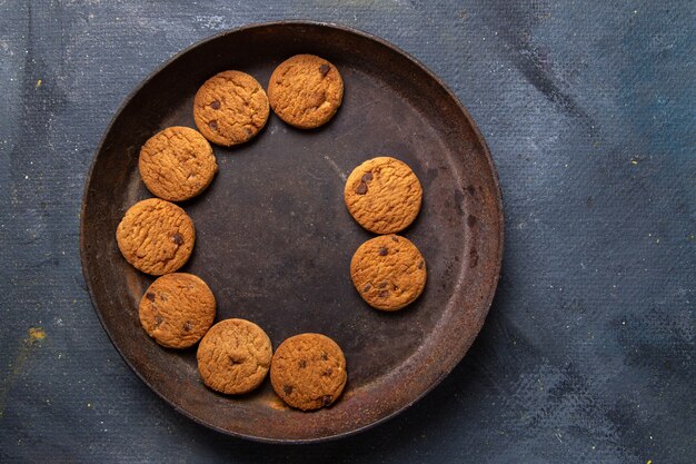 Vista dall'alto deliziosi biscotti al cioccolato all'interno del piatto rotondo marrone su sfondo grigio scuro biscotto biscotto dolce tè allo zucchero