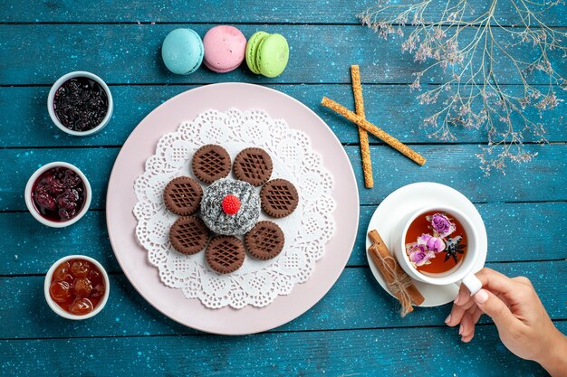 Vista dall'alto deliziosi biscotti al cioccolato con marmellata e tazza di tè su blu scrivania rustica biscotto biscotti da tè dolce zucchero torta