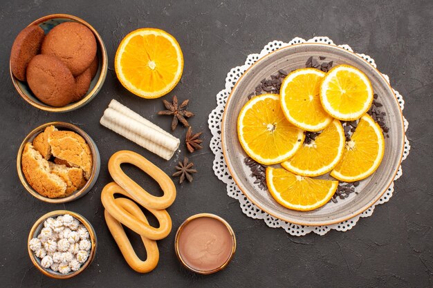 Vista dall'alto deliziosi biscotti con arance fresche su superficie scura biscotto biscotto torta di zucchero dolce da dessert