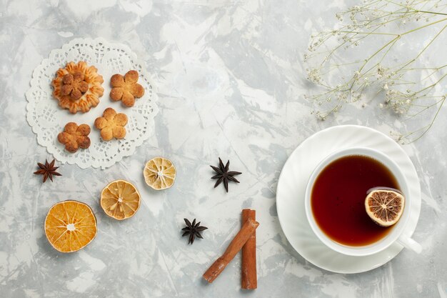 Vista dall'alto deliziosi biscotti con cannella e tazza di tè sulle patatine fritte dolci del tè dello zucchero del biscotto della scrivania bianca chiara