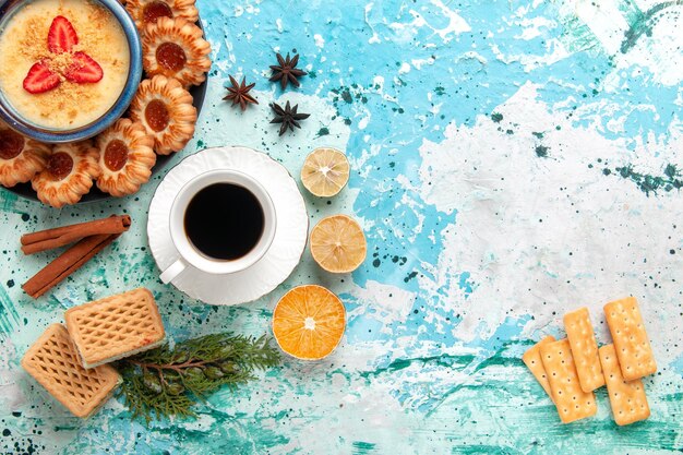 Vista dall'alto deliziosi biscotti con cialde di caffè e dessert alla fragola sulla scrivania blu