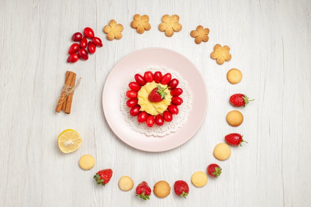 Vista dall'alto deliziosi biscotti con frutta e torta sulla scrivania bianca