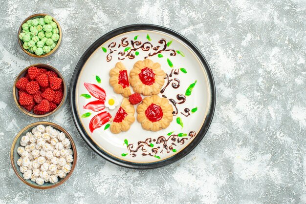 Vista dall'alto deliziosi biscotti con gelatina rossa e caramelle su sfondo bianco chiaro biscotto torta biscotto tè dolce