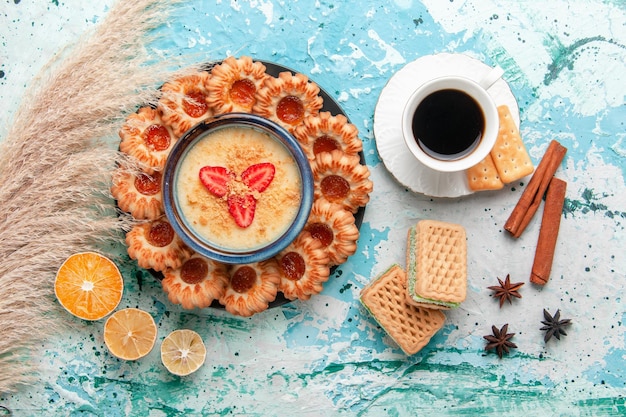 Vista dall'alto deliziosi biscotti con marmellata di caffè e dessert alla fragola su superficie azzurra