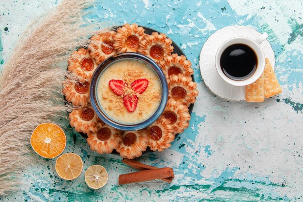 Vista dall'alto deliziosi biscotti con marmellata di caffè e dessert alla fragola sulla scrivania blu