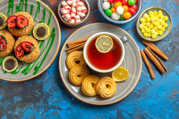 Vista dall'alto deliziosi biscotti con una tazza di tè e caramelle sulla frutta dolce del biscotto blu