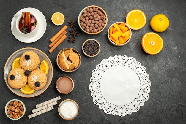Vista dall'alto deliziosi biscotti con una tazza di tè e fette d'arancia su una scrivania scura torta torta zucchero dessert biscotto tè