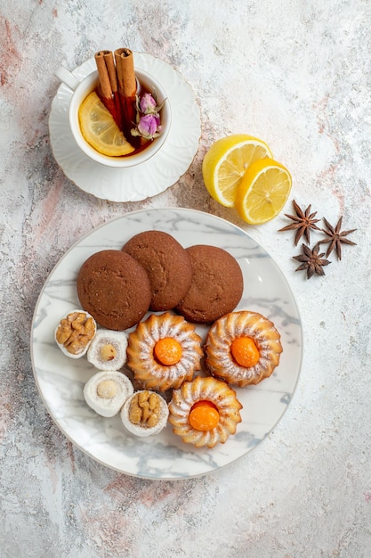 Vista dall'alto deliziosi biscotti con una tazza di tè su sfondo bianco biscotto biscotto dolce torta zucchero tè