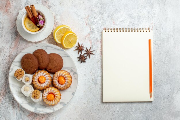 Vista dall'alto deliziosi biscotti con una tazza di tè su sfondo bianco biscotto zucchero biscotto torta dolce tè