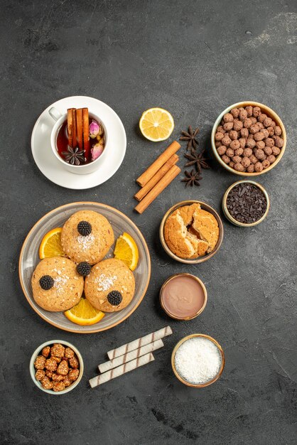 Vista dall'alto deliziosi biscotti con una tazza di tè sulla superficie scura torta torta zucchero dessert biscotto tè