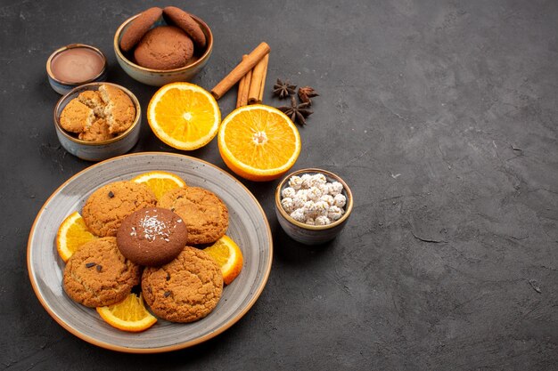 Vista dall'alto deliziosi biscotti di sabbia con arance fresche a fette su sfondo scuro biscotto alla frutta biscotto dolce zucchero agli agrumi