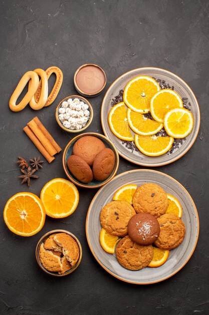 Vista dall'alto deliziosi biscotti di sabbia con arance fresche su sfondo scuro biscotto zucchero frutta biscotto dolce agrumi