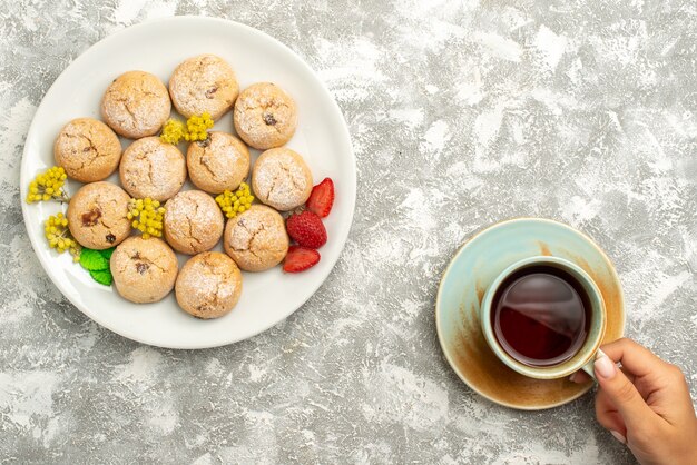 Vista dall'alto deliziosi biscotti di zucchero con una tazza di tè su sfondo bianco biscotto biscotto zucchero torta tè dolce