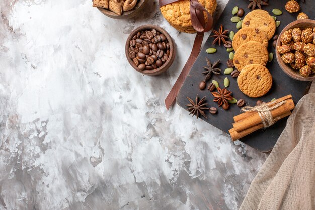 Vista dall'alto deliziosi biscotti dolci con semi di caffè e tazza di caffè sul tavolo luminoso