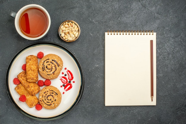 Vista dall'alto deliziosi biscotti dolci con una tazza di tè su uno spazio grigio